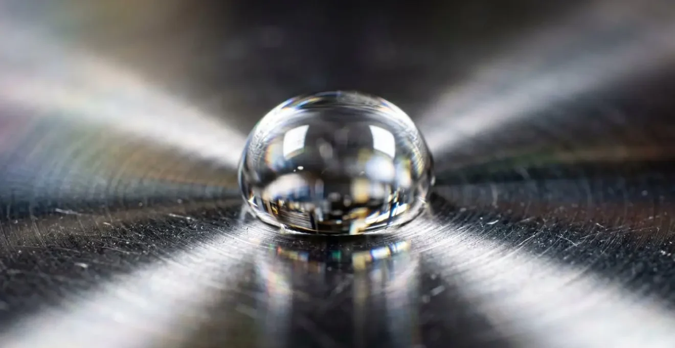 Détail macro d'une goutte d'eau sur une surface réfléchissante symbolisant la concentration